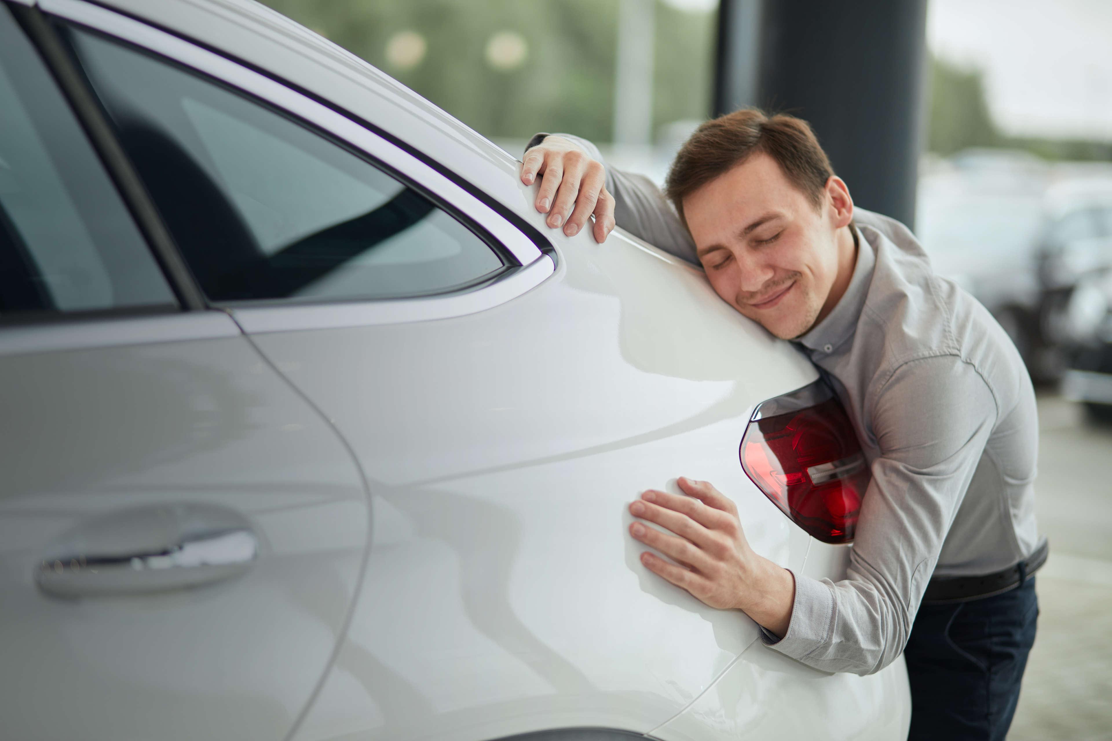 Mies halaa hymyillen autoaan.